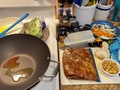 Tonight's Dinner: Cashew Chicken with Snow Peas on Shirataki Lo Mein.  And Mandu (Korean Pot Stickers). Dinner prep began mid-afternoon with cutting up #Chicken thighs into 1" cubes and then #velveting (Asian method of tenderizing using corn or potato starch) and marinating for a couple hours in mix of soy sauce (light & dark), rice vinegar, Shaohsing wine. While chicken marinated, Shirataki noodles (an almost zero-carb noodle made from #Konjac yams) drained and were patted dry. Onion was julienned, carrots sliced, and tips removed from #SnowPeas. One egg scrambled to go in #LoMein.  When ready to begin cooking I heated wok and a small skillet for the #Mandu. Begin with adding some Seasame oil and garlic chili oil to pans, then position Mandu on sides in small and cover, and add Shirataki to hot wok. Stir-fry noodles and add carrots and onions, and continue stirring occasionally.  Turn Mandu to sit on their bottoms and continue browning while covered. After carrots have softened and onions begin to brown, clear center of wok and add egg and scramble, then stir in noodles, mix well and place in serving bowl.  Return #wok to heat and get very hot, add another splash of oils. Turn Mandu onto last side to finish browning.  While wok reheats, drain chicken saving marinade, then add to hot wok. Stir-fry chicken vigorously so it doesn't stick and scorch. When chicken is cooked through and outside begins to crisp, mix in #Cashews, then the saved marinade, stir well, top with Snow Peas cover and lower heat to medium. Let chicken and peas simmer and steam while plating Mandu, then serve #CashewChicken over Lo Mein. I had four large-ish boneless chicken thighs left from a 10-pack that I opened this afternoon to start another culinary project that I'll share in a couple days. Yes the 4 thighs made a LOT of Cashew Chicken and I'll portion and freeze the extra. #TonightsDinner