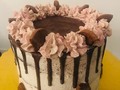 Hermosa torta de chocolate cubierta y rellena con butter cream de galleta, con goteo de chocolate oscuro.