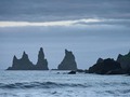 Zwei kämpfende Trolle, die ein dreimastiges Schiff an Land bringen wollten und vom Sonnenaufgang überrascht zu Stein wurden. Die Basaltformation Reynisdrangar bei Vík í Mýrdal. Island. 2022.